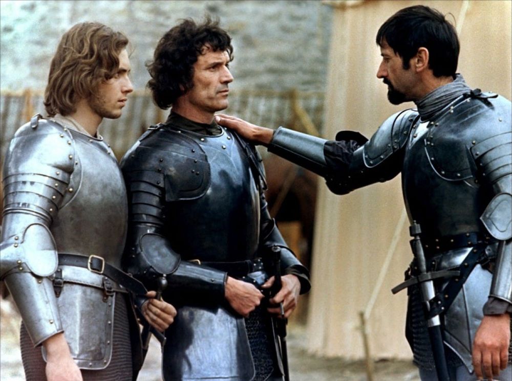 Three knights in medieval armor. King Arthur has his right hand on Lancelot's left shoulder. From Robert Bresson's Lancelot du Lac (1974)