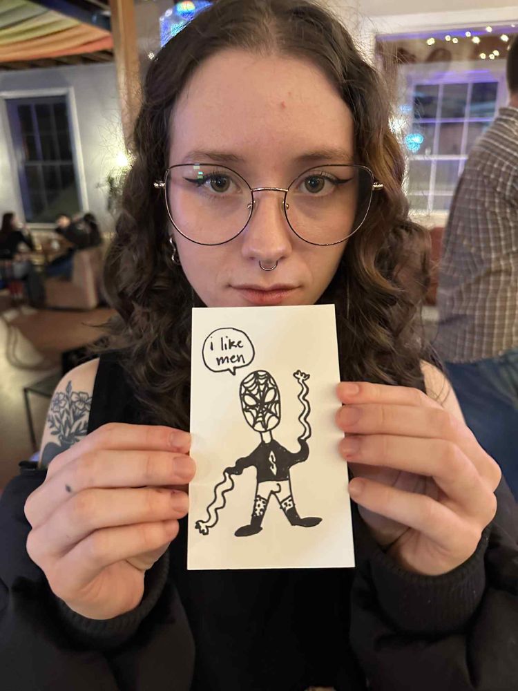 photo of a woman wearing large glasses holding a hand drawn picture of  