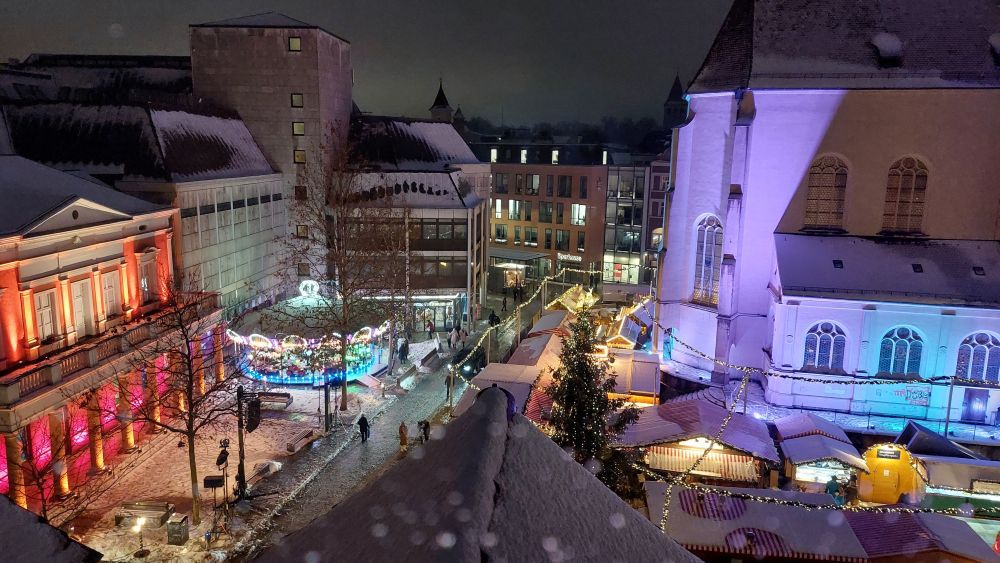 Blick von oben auf den bunt beleuchteten Christkindlmarkt am Neupfarrplatz in Regensburg.