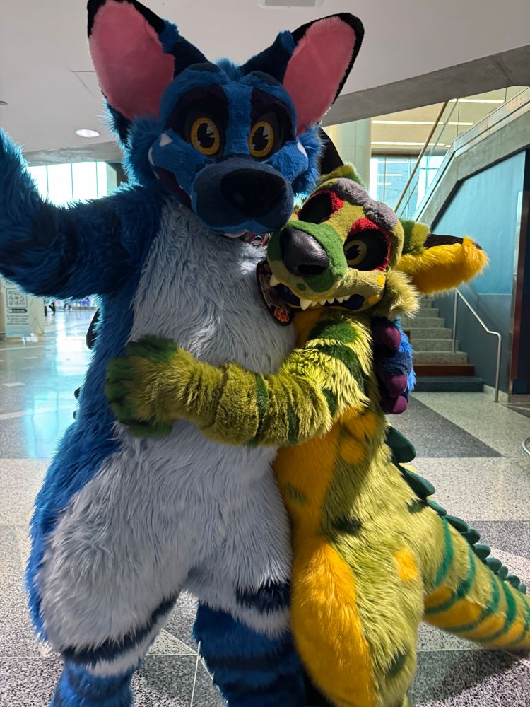 Buster and Jai, two jackodile fursuits. Jai is hugging Buster