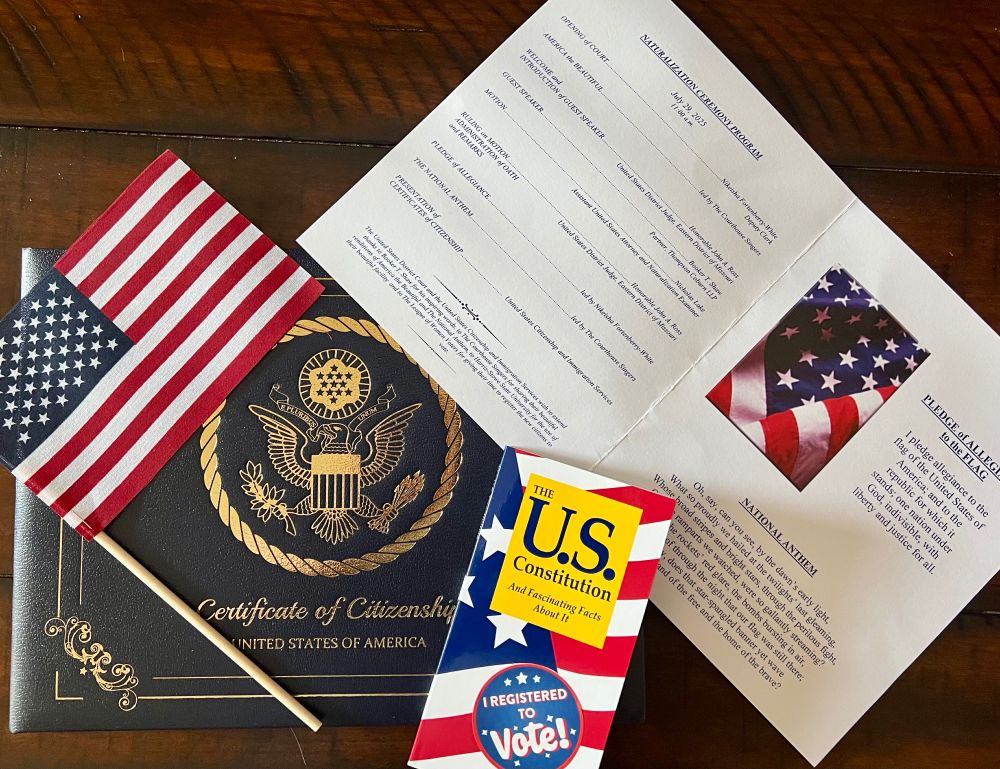 An American Flag, US Citizen Certificate, US Constitution and Oath ceremony Program from a Naturalization Ceremony.