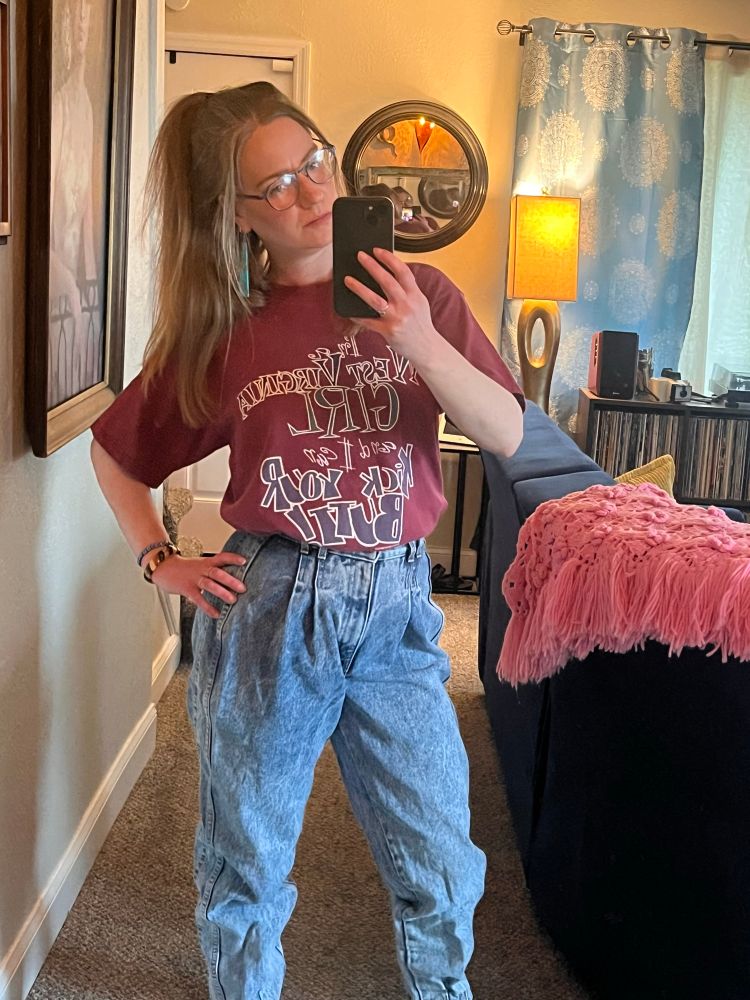 Ghoulihan a blonde woman with a high half pony maroon “I’m a wv girl and I can kick your butt” tee and blue jeans