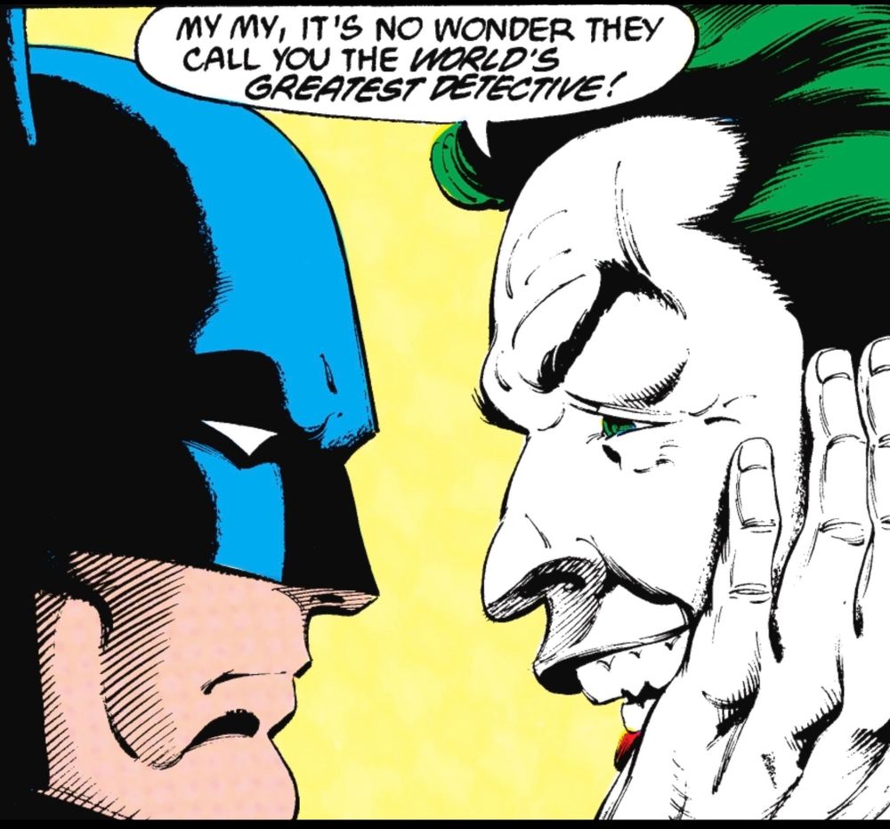 Close-up of the Batman and Joker’s faces in profile as a stare at each other, their faces inches apart. The Joker rests his hand on the side of his face as he says, “My my, it’s no wonder they call you the WORLDS GREATEST DETECTIVE!“