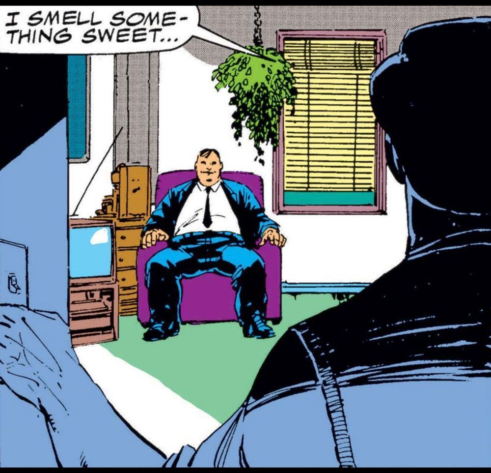 A man walks into a room, his hand by the light switch as he sees facing him and the reader, a man in a suit and tie sitting in a purple chair next to an old-fashioned television, seemingly what they smile on his face and his legs spread wide. The man who entered the room says, “I smell something sweet….“ 