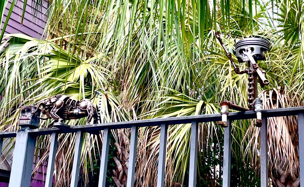 Statues on top of fence made up of misc metal bits