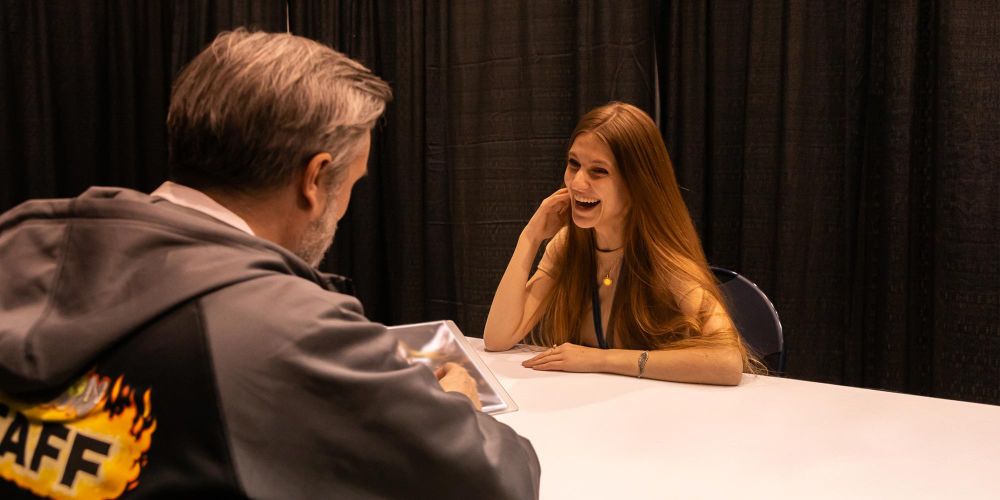 Photo of a smiling female artist meeting with a Wizards of the Coast art director.
