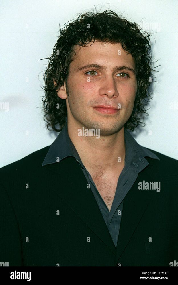 Young Jeremy Sisto with longer hair that's dark and curly. He's wearing a dark grey shirt and black coat. There is a watermark over the image repeatedly that is mostly the letter a but also says alamy occasionally 