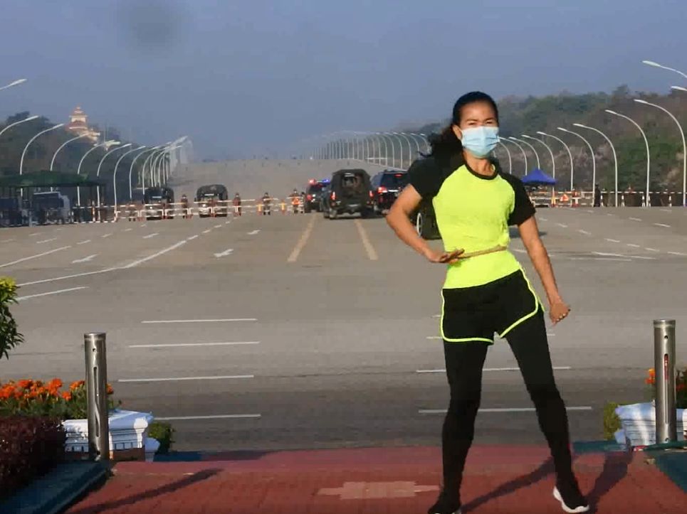 The famous photo of a Myanmar aerobics instructor performing to camera, oblivious to the military vehicles in the background heading to do their coup.