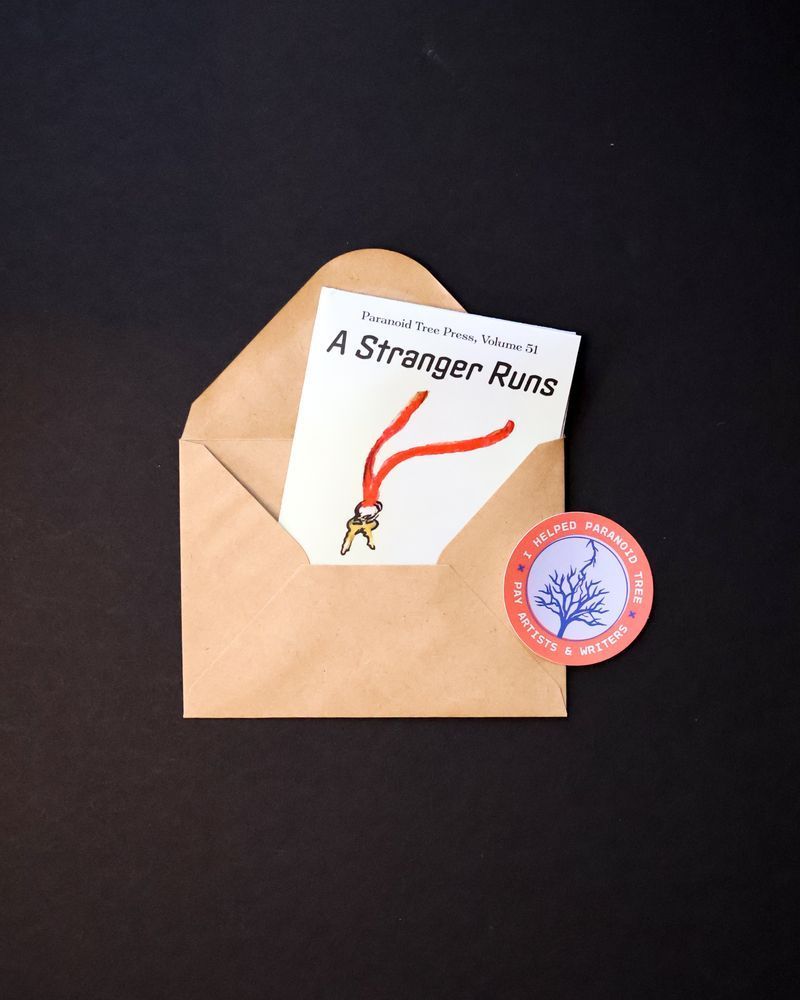 Volume 51 folded up and tucked into an envelope, alongside a Paranoid Tree sticker. This is how the issue arrives in the mail to print subscribers.