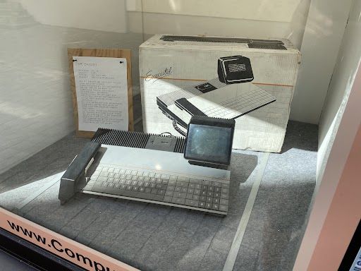Im Schaufenster des Computeums ist eine Art Tastaturcomputer zu sehen. Links neben der Tastatur ist ein Telephonhörer in einer Halterung. Oberhalb der Tastatur ist ein Micro-Kassetten-Laufwerk und rechts davon ein winziger, schwenkbarer Röhrenmonitor. Das Design ist sehr kantig, wie aus einem SF-Film der 70er, insgesamt keilförmig wie ein DeLorean. Würde perfekt in die Ausstattung der Serie UFO passen. Dahinter steht die original Schachtel sowie daneben eine Tafel mit einer Beschreibung.