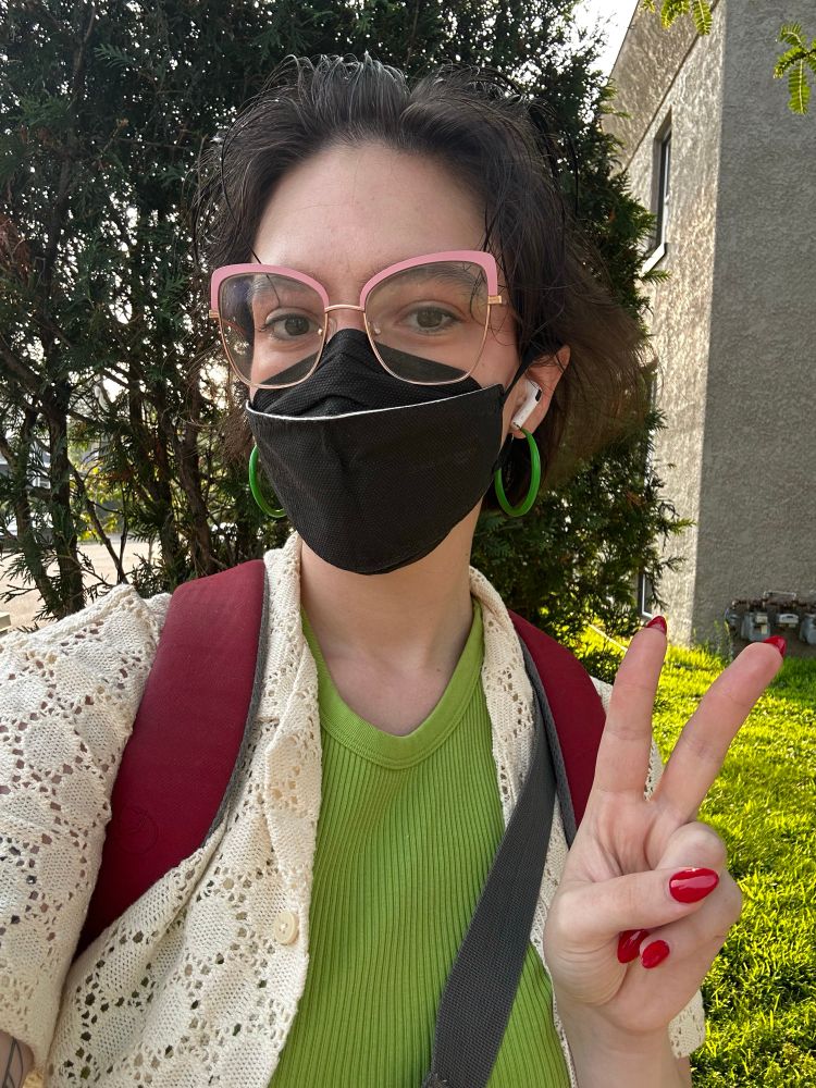 a selfie of me, a white lady, wearing a black face mask and throwing a v millennial peace sign