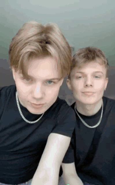 two young men wearing black shirts and silver chains