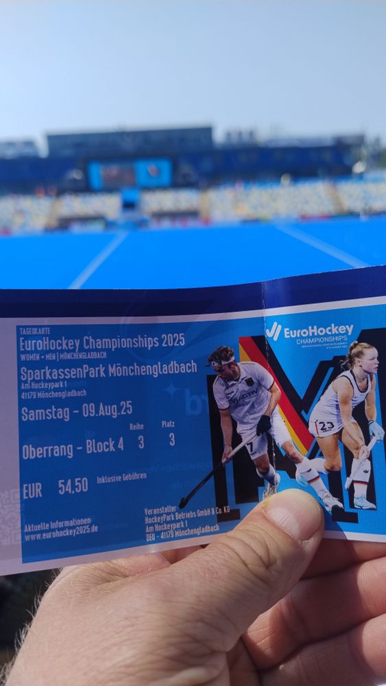 Eintrittskarte vor einem blauen Hockeyplatz.
