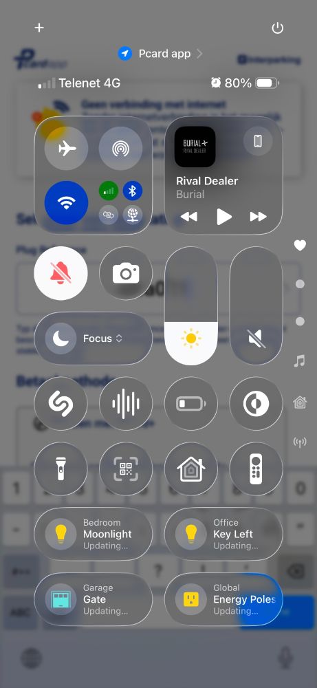 iOS 26 Control Center screen showing connectivity toggles, media player, brightness and volume sliders, focus mode, and smart home device controls. Accessibility issues include small touch targets, low contrast icons on blurred backgrounds, inconsistent labeling of controls, and crowded layout that may hinder screen reader navigation.
