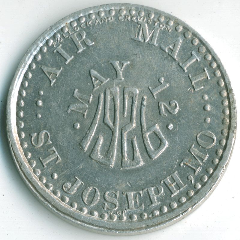 Aluminum coin with an Art Deco 1926 at its center, below a more conventionally lettered “May 12”. 
Curving around the coin at the top: “Air Mail”; at the bottom: “St. Joseph, MO”. 
In tiny letters at the edge: top, “Pollock and Creviston”, my grandfather’s brother’s jewelry business; bottom, the initials WGP for my grandfather, William Grover Pollock.