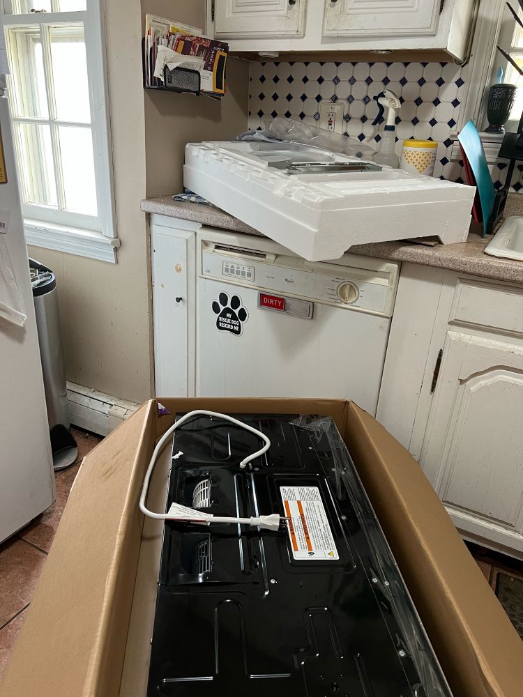 As described, the room being a kitchen and the microwave being half-unpacked on the floor, looking enormous.