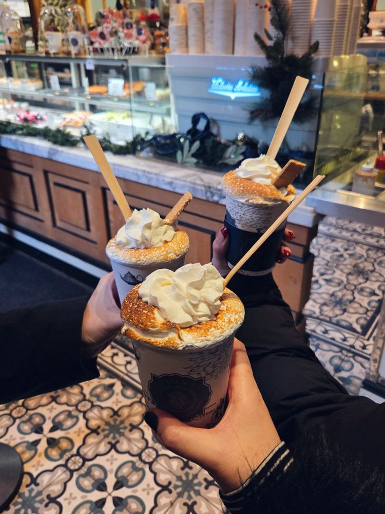 3 hands hold fancy hot chocolates with whip cream and toasted marshmallow rims 
