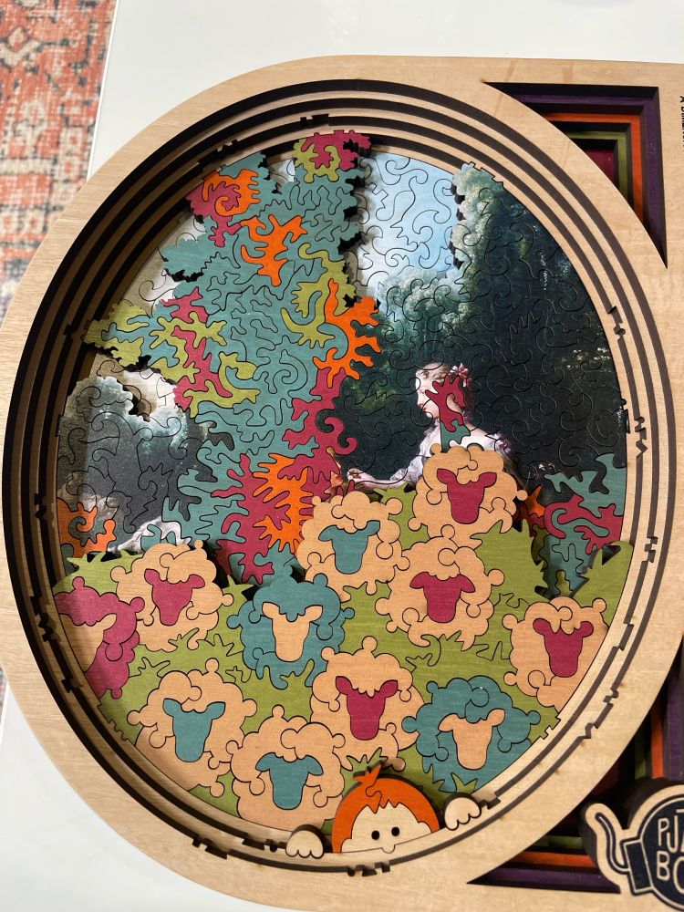 Most of the painted scene is gone, and about 60% of the visible puzzle is a colorful scene of cartoon sheep in front of a psychedelic tree. Some crazy spirals are creeping into the painted humans’ bodies and faces. 