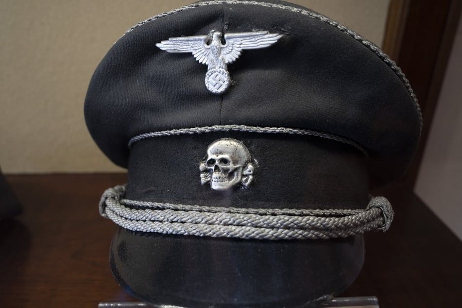 An image showing the nazi party insignia and the totenkopf pin on a nazi SS hat.