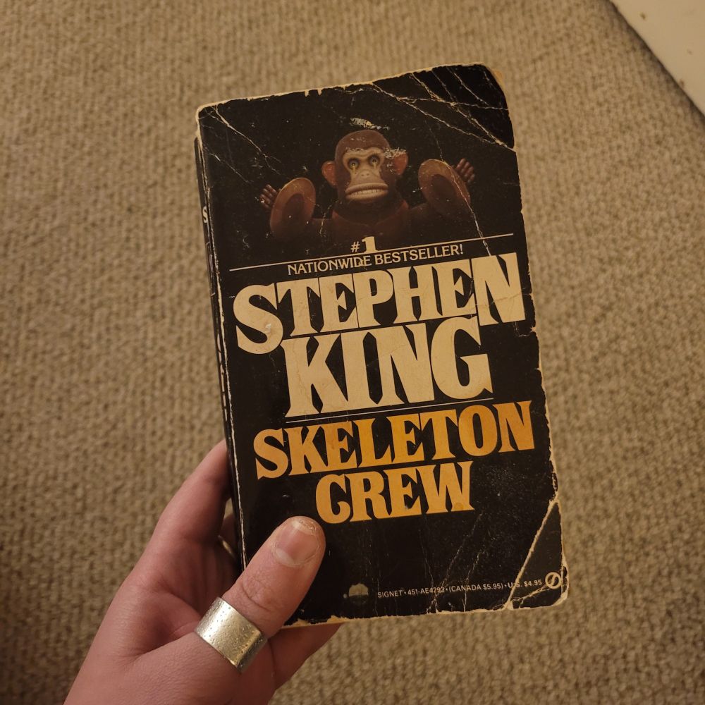Old paperback of skeleton crew collection of short stories by Stephen king with monkey holding chimes at top