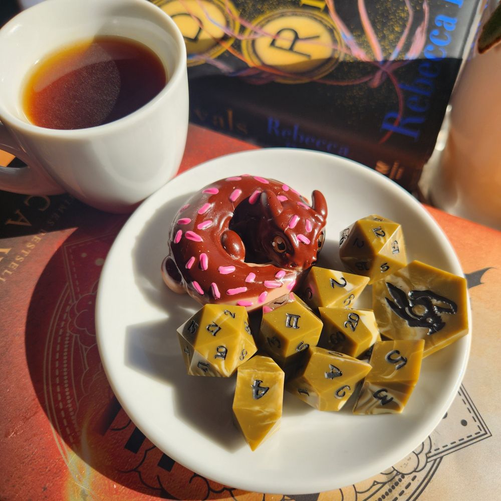 A warm setting with a cup of coffee, Cappuccino dice, and a donut dragon