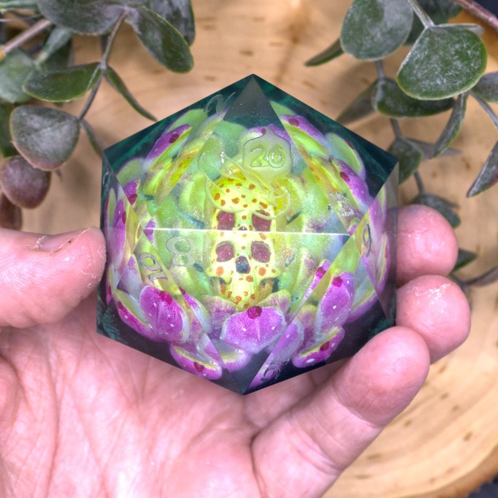 A baseball sized D20 with a Blooming pink lotus designs inside. At the center of the flower is a human skull.