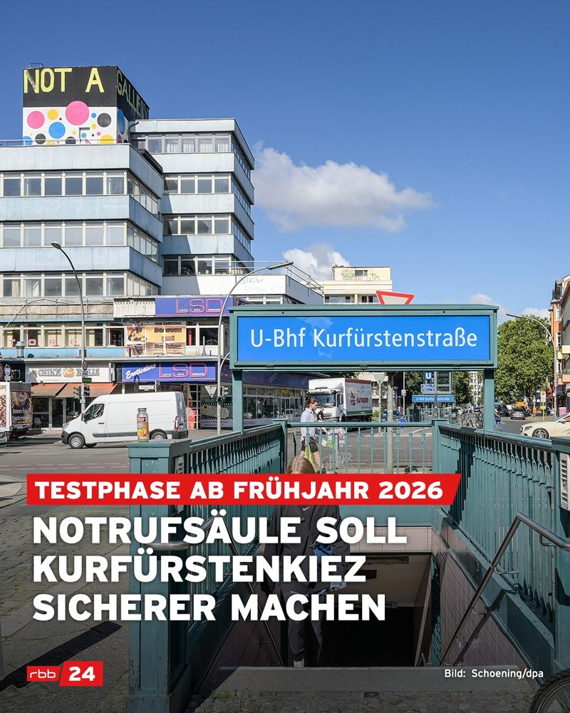 Tagesaufnahme vom U-Bahnhof Kurfürstenstraße in Berlin mit Blick auf den Eingang zur Station. Im Vordergrund steigt eine Person die Treppe zur U-Bahn hinab. Darüber eingeblendet steht in großen weißen Buchstaben: „Notrufsäule soll Kurfürstenkiez sicherer machen“. In einem roten Balken darüber: „Testphase ab Frühjahr 2026“. Im Hintergrund ist ein mehrstöckiges Gebäude mit dem auffälligen Schriftzug „NOT A GALLERY“ auf dem Dach sowie bunten Punkten zu sehen. U-Bahn-Schild „U-Bhf Kurfürstenstraße“ mittig im Bild. Unten links Logo von rbb24, unten rechts Bildnachweis: Schoening/dpa.