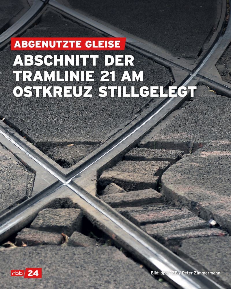 Nahaufnahme eines abgenutzten Straßenbahn-Gleisübergangs mit stark beschädigtem Asphalt und freiliegenden Pflastersteinen. In der Bildmitte kreuzen sich zwei Schienenstränge. Im oberen Bildbereich steht in weißer, fetter Schrift auf schwarzem Hintergrund: „ABSCHNITT DER TRAMLINIE 21 AM OSTKREUZ STILLGELEGT“, darüber auf rotem Balken: „ABGENUTZTE GLEISE“. Unten links das rbb24-Logo, unten rechts die Quellenangabe: „Bild: dpa / ZB / Peter Zimmermann“.