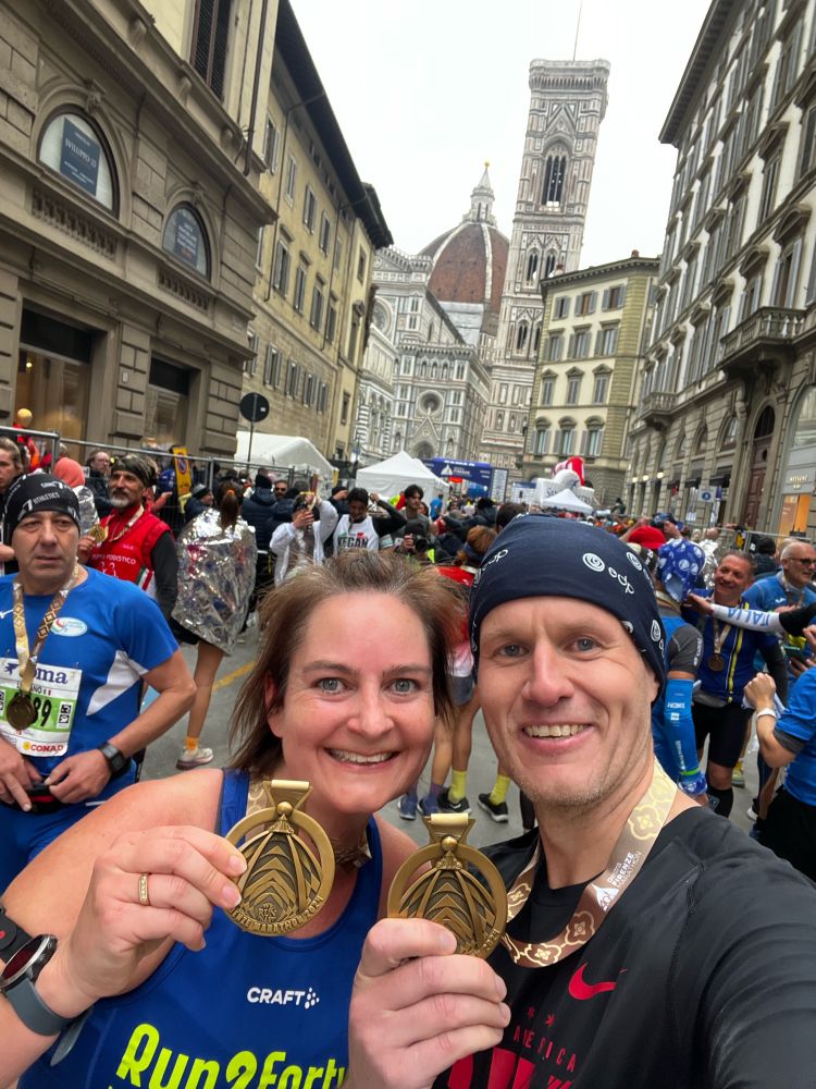 Two persons in running outfit holding medals