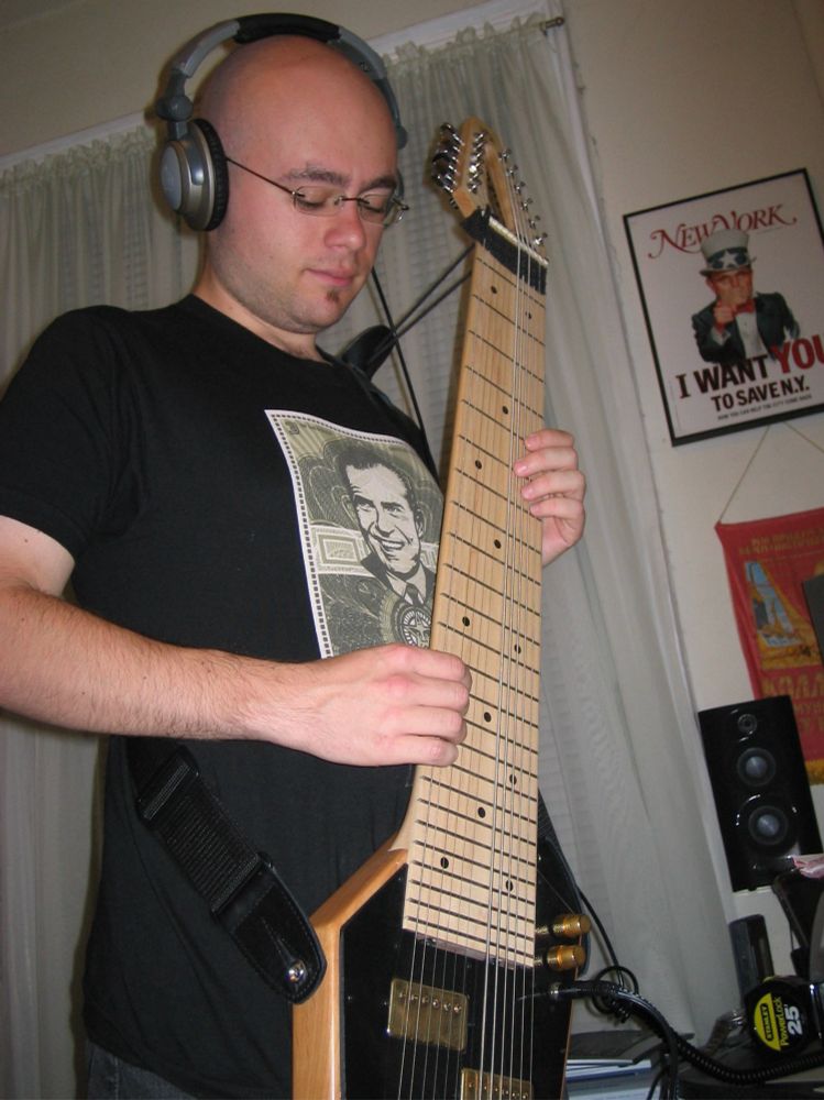 Bald-headed young man playing a Mobius Megatar while wearing headphones