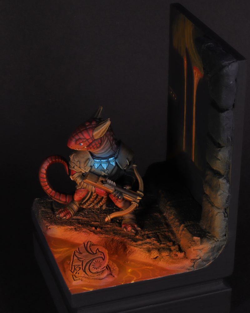 Pathfinder Red Kobold Miniature, Illuminated by a pool of Lava, holding a crossbow, and warded by a glowing blue necklace. Photo #2.