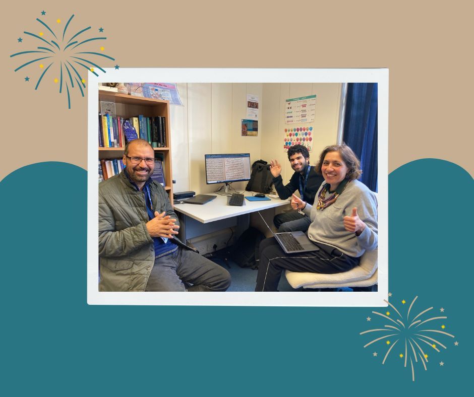 Image features a teal and gold/brown background, with images of fireworks exploding. There is a frame in the centre, around a photograph of three people smiling, one with hands clasped, one with two thumbs up and one waving. The backdrop is an office, with three computers in the background, a bookcase and many posters on the walls.