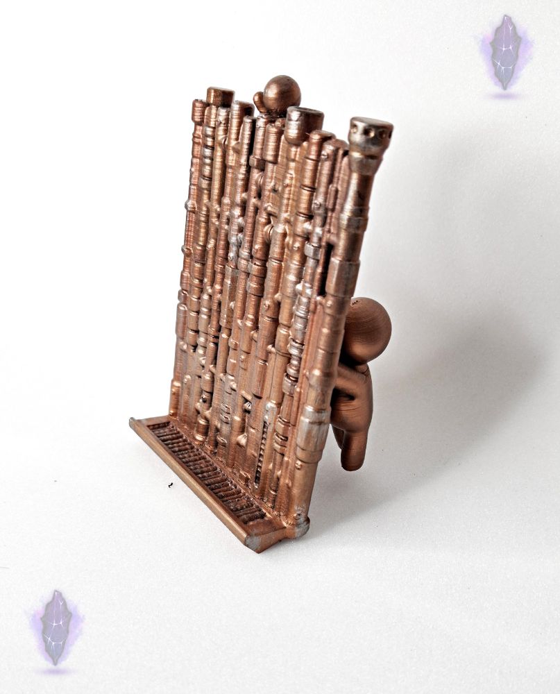 Un porte telephone. au dos se trouve plein de petits personnage tenant la plaque droite afin de tenir le telephone. Il arbore des motifs de tuyau couleurs cuivre pour lui donner un style steampunk