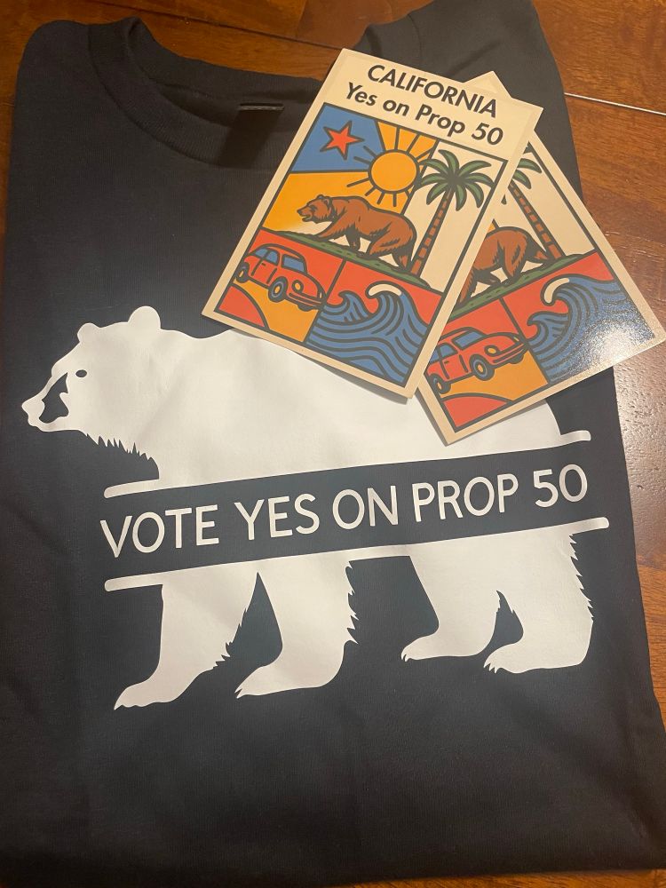 Folded black tshirt with a white CA bear and “ vote yes on Prop 50 “ and 2 colorful postcards that read “ California YES on Prop 50 “