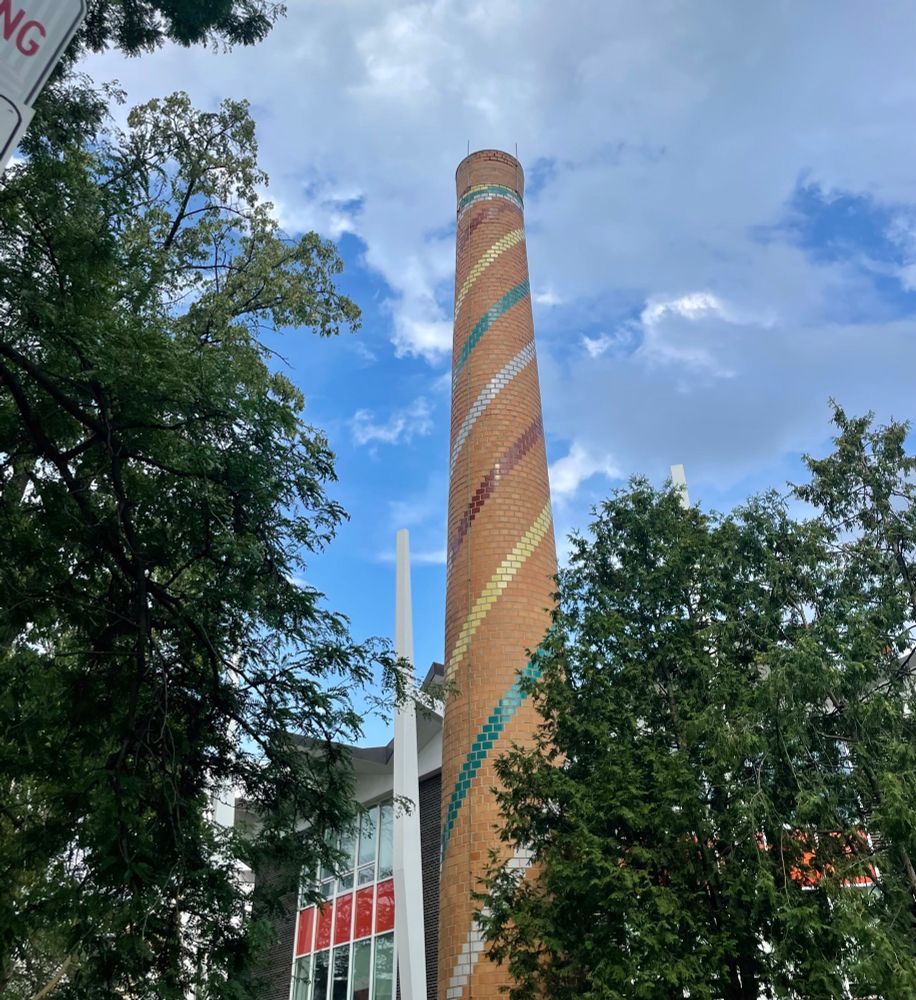 Brick chimney stack outside Lord Lansdowne Junior Public School with painted decorative ribbons of red, yellow, white and green.