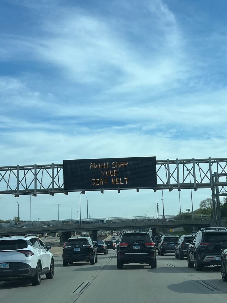 Customized traffic sign on an highway states “Aww Snap Your Seatbelt”.