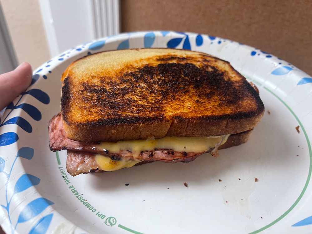 A picture of a sandwich made of thick toast, several thick slices of smoked spiral ham, and a layer of cheddar cheese between each layer of ham. 