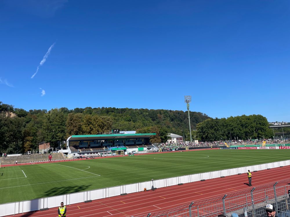 Blick auf das Stadion Oberwerth in Koblenz aus dem Gästeblock bei strahlendem Sonnenschein und blauem wolkenfreien Hinmel