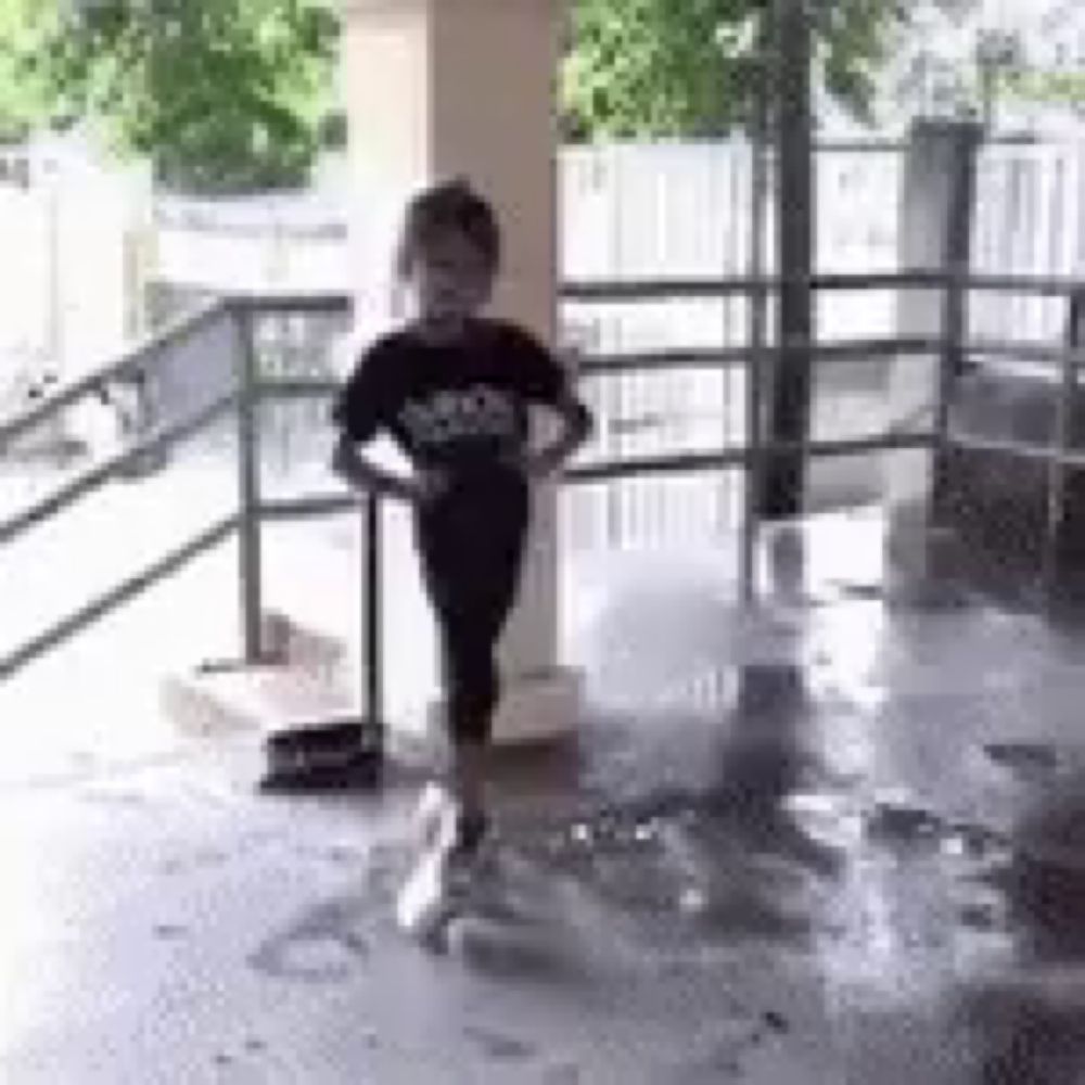 a young boy is standing next to a broom on a wet floor .