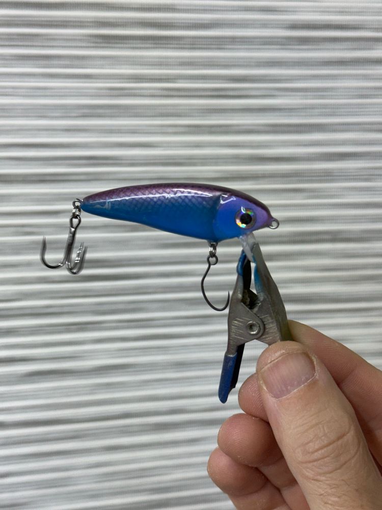 A jerk bait fishing lure in blue and purple with wine sparkle scales