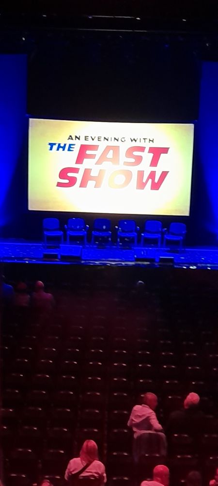 The stage at the Cambridge Corn Exchange with a banner reading "An evening with the Fast Show"