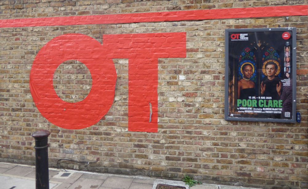 Brick wall with OT in big red capitals left, poster for Poor Clare depicting two lead actors in a stained-glass idiom right.