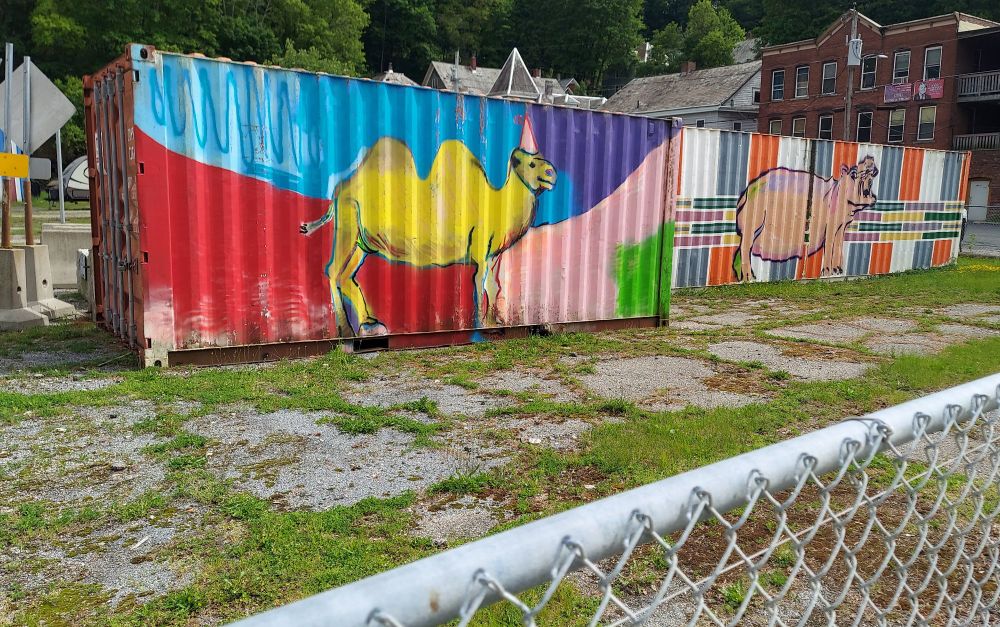 Two brightly painted storage containers. One has a camel on it and the other has a hippo. If you squint, you can see the groundhog on the ground in front of the camel's feet.