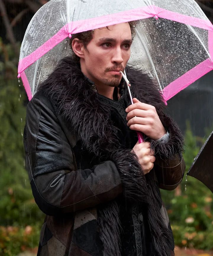 Klaus from Umbrella Academy holding unto his pink umbrella