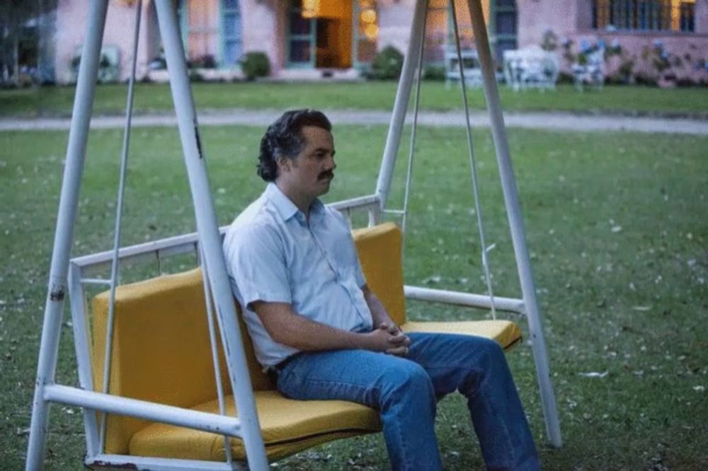 a man with a mustache sits on a yellow swing