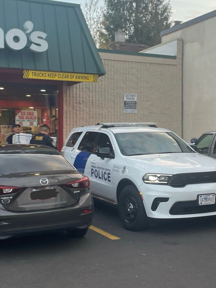 photo taken outside of a domino’s pizza showing two federal police officers exiting the domino’s carrying probably 15 pizzas, and heading to their ugly police SUV. 