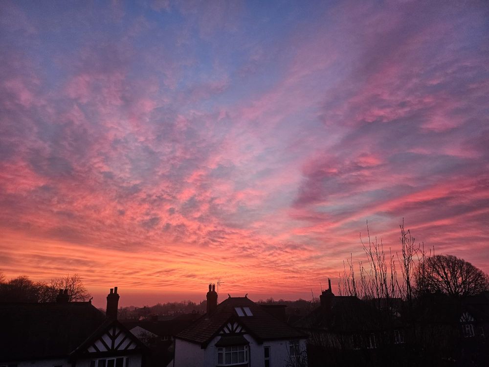 Sunrise over harrogate. Rooftops are in silhoutte, the sky moves through orange to blue