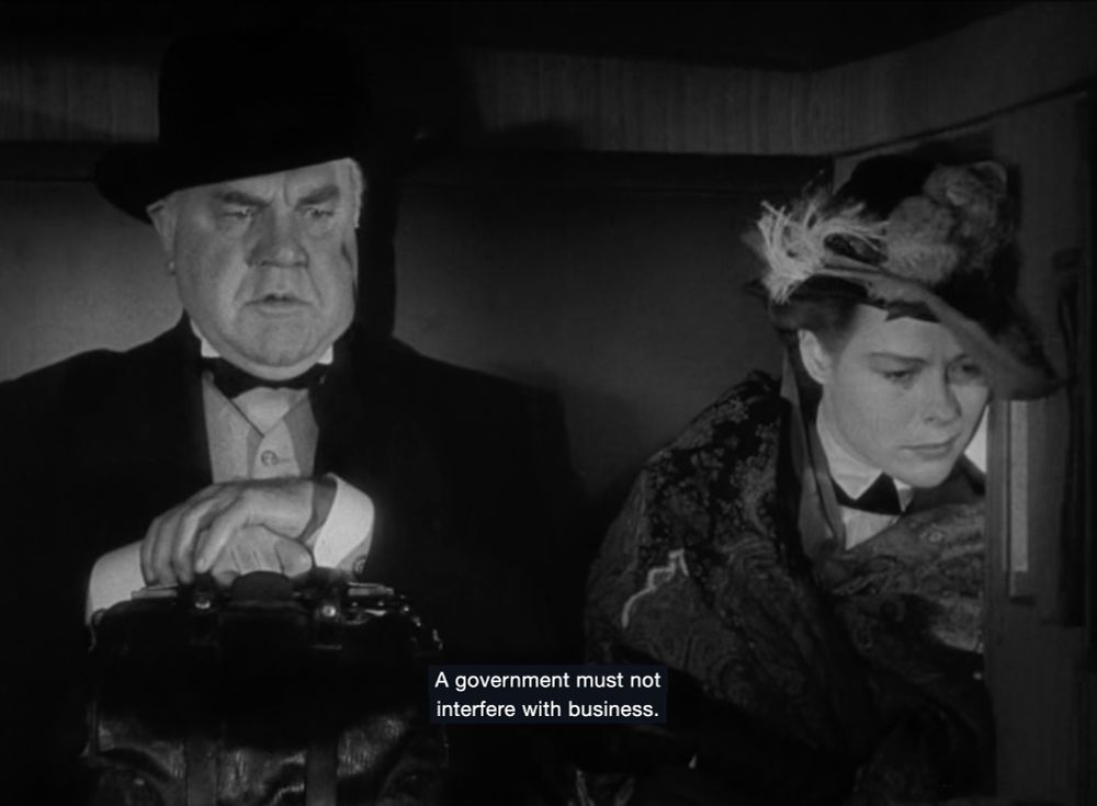 Pompous Hoover-looking mf-er states "A government must not interfere with businesses" while the woman next to him in a stagecoach looks nauseated and leans towards the wind.