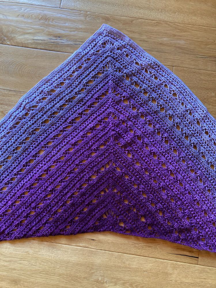 Closer look at the crocheted shawl in fading purple colors to see the pattern.
