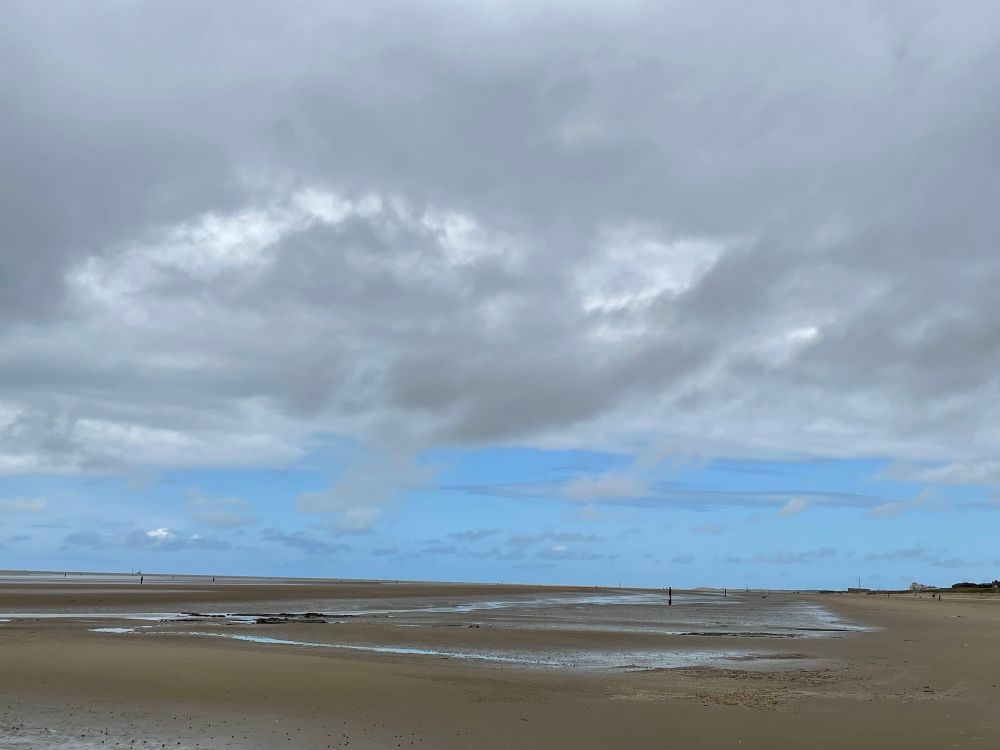 Big expanse of beach with blue sky and grey cloud 